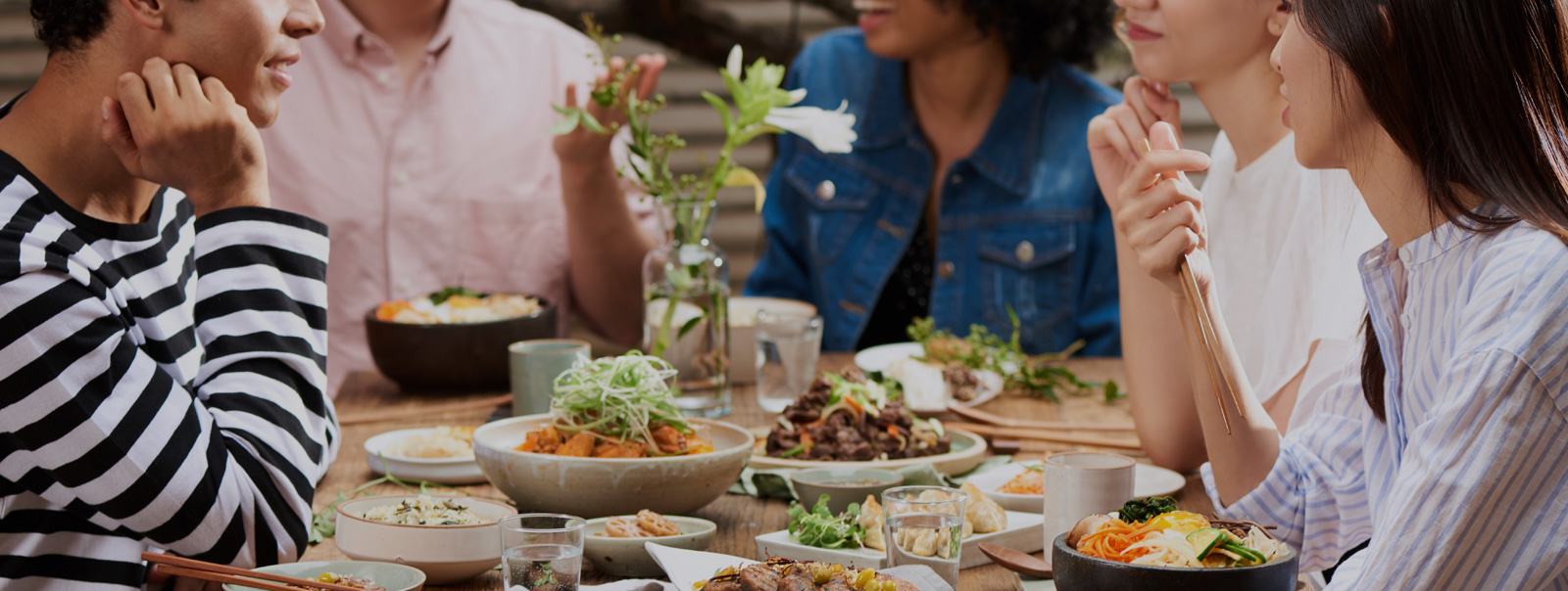 한국 음식이 놓인 테이블에 둘러 앉은 다양한 국적의 사람들 이미지